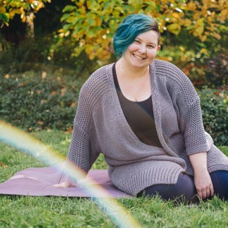 Sarah sits in a park, she is smiling at the camera