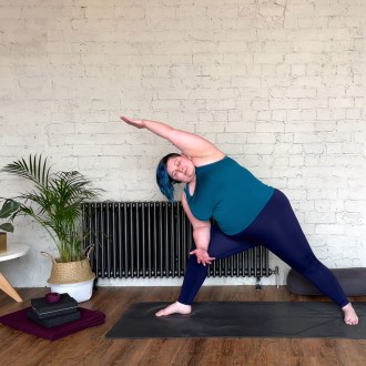 Sarah is on a yoga mat in a posture called Extended Side Angle Pose